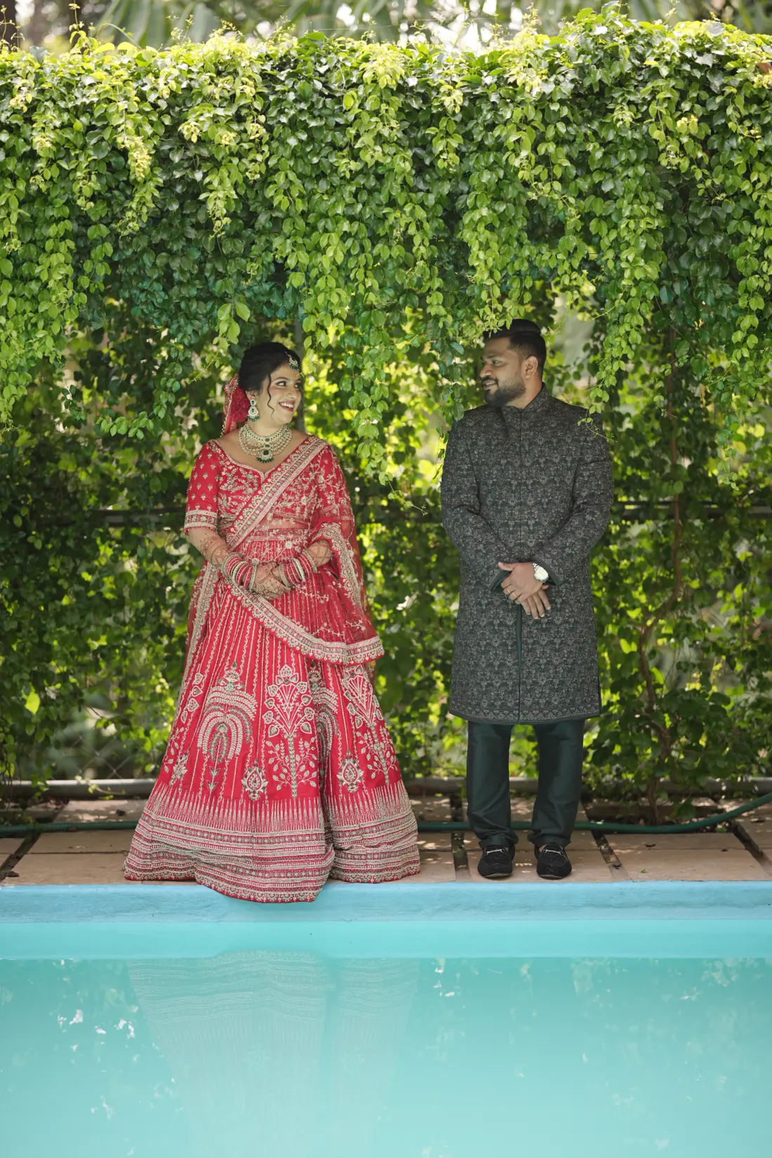 Diya and Renju standing together beside the garden pool